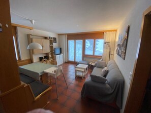 A compact living space with a bed, a sofa, a small table, a TV, and a window. - Alicia, (Grächen), 1901 by Interhome (Grächen)