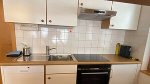 A compact kitchen with a dishwasher, oven, sink, and a stove top. - Alicia, (Grächen), 1901 by Interhome (Grächen)