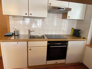 A compact kitchen with a dishwasher, oven, sink, and a stove top. - Alicia, (Grächen), 1901 by Interhome (Grächen)