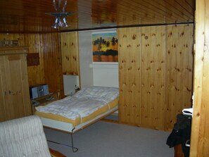 A bedroom with a bed, a desk with a computer, a chair, and a wooden wardrobe. - Sunnuschy, (Grächen), 1056 by Interhome (Grächen)