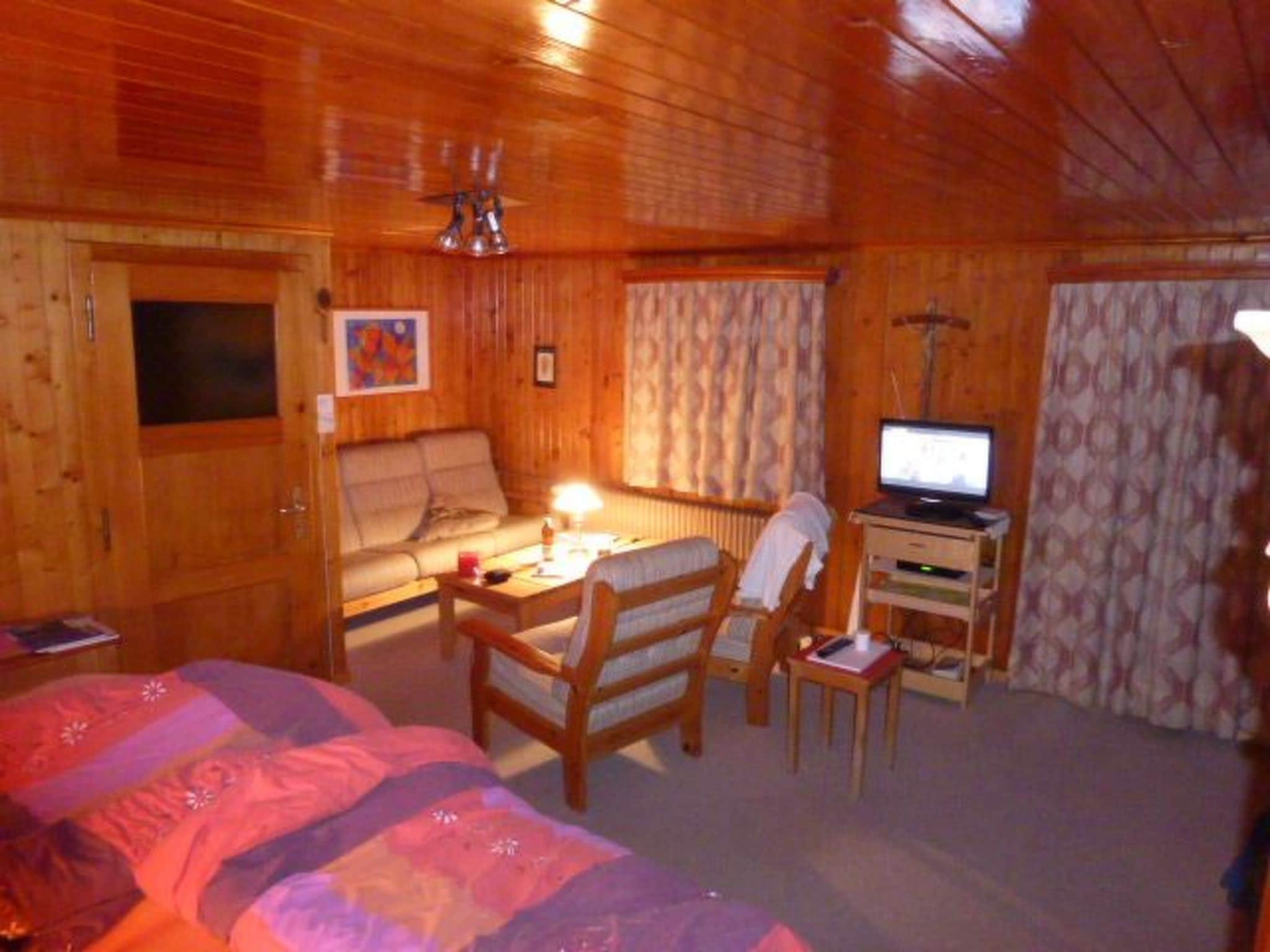 A cozy room with a bed, a desk, a chair, and a television.