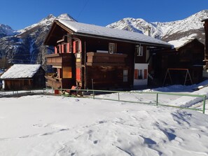 A wooden chalet with a balcony, set against a snowy mountain backdrop. - Sunnuschy, (Grächen), 1056 by Interhome (Grächen)
