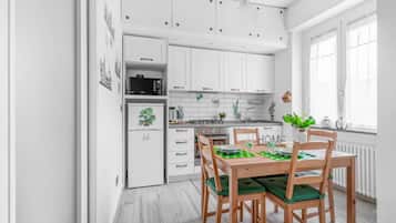 Una cucina moderna con mobili bianchi, un tavolo da pranzo con sedie e una finestra con tende.