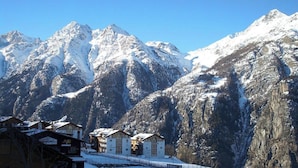 A mountain resort with snow-covered peaks, chalet-style buildings, and a clear sky. - Castello, (Grächen), 1322 by Interhome (Grächen)