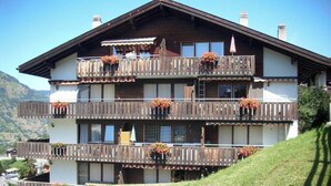 A multi-story building with balconies, each adorned with flower baskets. - Castello, (Grächen), 1322 by Interhome (Grächen)