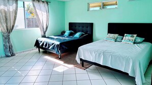 Quarto com duas camas, janela com cortinas, ar-condicionado e ventilador de teto.