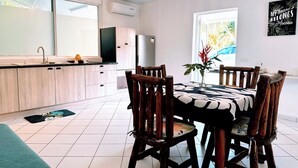 Uma cozinha moderna com área de refeições, com uma janela grande, armários de madeira e piso ladrilhado.