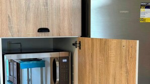 A kitchen with a microwave, a refrigerator, and wooden cabinetry.