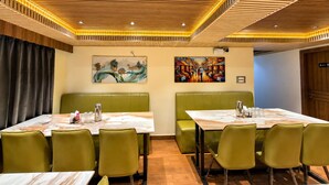 Un restaurante con techo de madera, asientos tipo cabina verdes y mesas con cubierta de mármol.