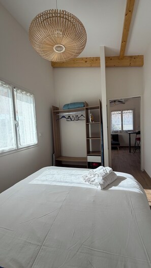 A bedroom with a bed, a wardrobe, a desk, and a hanging light fixture. - BEACH HOUSE, Vensac Océan, just outside Montalivet: a cozy little getaway for two! (Vensac)