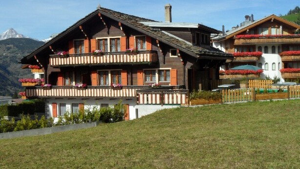 A two-story chalet with balconies, a wooden facade, and a mountainous backdrop. - Chalet Matten, (Grächen), by Interhome (Grächen)