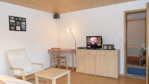 A living room with a television, a chair, a table, and a cabinet. - Chalet Matten, (Grächen), by Interhome (Grächen)