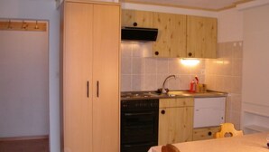 A compact kitchen with wooden cabinets, a stove, and a sink. - Chalet Matten, (Grächen), by Interhome (Grächen)