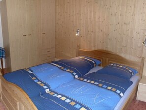 Ein Zimmer mit Holzwänden, einem Bett, einem Nachttisch und einem Kleiderschrank.