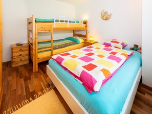 Quarto com uma cama de solteiro, uma cama individual, uma mesinha de cabeceira, um abajur e um enfeite na parede.