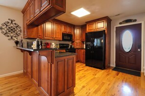Eine Küche mit Holzausstattung, einem schwarzen Kühlschrank und einer Mikrowelle.