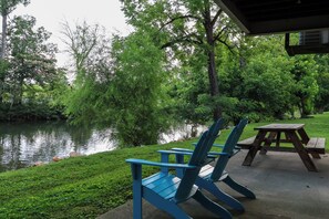Un espacio de estar junto al lago con sillas Adirondack y una mesa de picnic.
