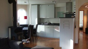 Ett kompakt bostadsutrymme med en matplats, ett litet kök och en liten sittgrupp.