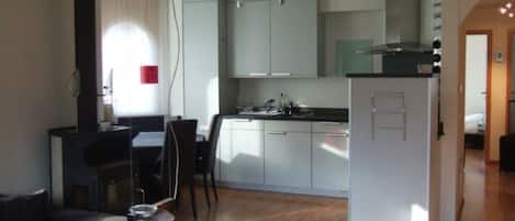 Un espacio habitable compacto con kitchenette, comedor y zona de estar separada.
