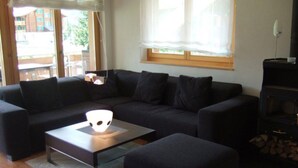A modern living room with a sectional sofa, a glass coffee table, and a fireplace.