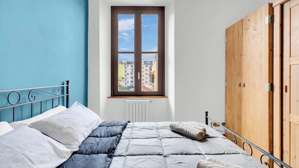 A bedroom with a bed, a window, and a wardrobe. - CO14 [Central] • Comfort • (Milano)