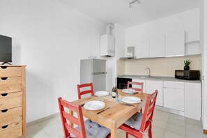 Eine moderne Küche mit weißen Schränken, einem Holztisch mit vier Stühlen und einer Mikrowelle auf der Arbeitsplatte.