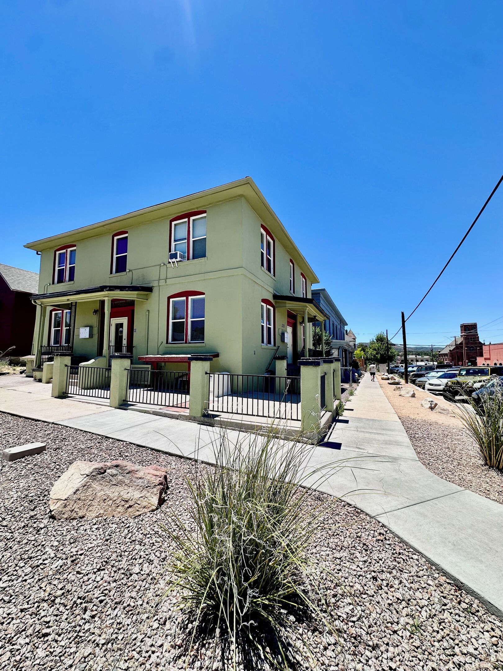 A two-story building with a porch and a fenced yard.