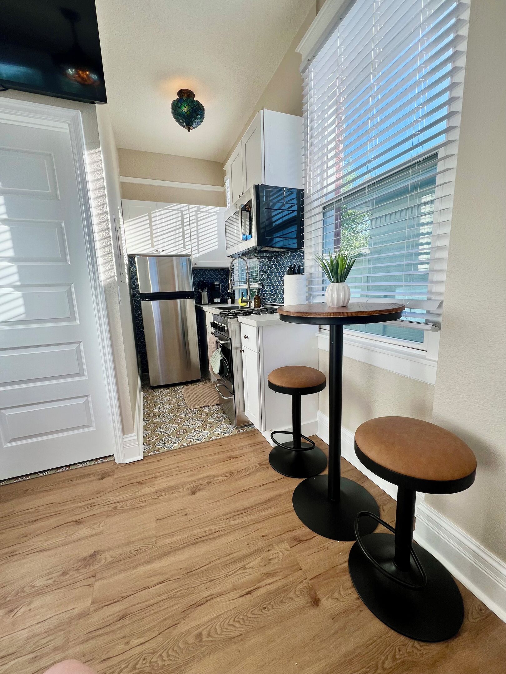 Una cocina moderna con refrigerador, microondas y una pequeña zona de comedor con taburetes.