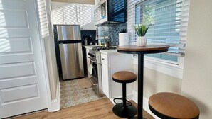 Eine moderne Küche mit Kühlschrank, Mikrowelle und einer kleinen Essecke mit Barhocker.