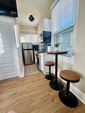 A modern kitchen with a refrigerator, microwave, and a small dining area with stools. - Luxury Downtown Studio • 2 Blocks to the Square (Prescott)