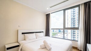 Hotellihuone, jossa on suuri sänky, yöpöytä, ikkuna, josta on näkymä kaupunkiin, ja kattoilmanvaihtoaukko.
