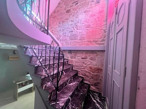 A staircase with a stone wall background and a door on the right.