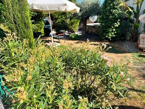 A garden with a patio area, outdoor furniture, and a variety of plants.
