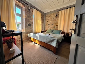 A bedroom with a bed, a bedside table, a lamp, and a window with curtains.