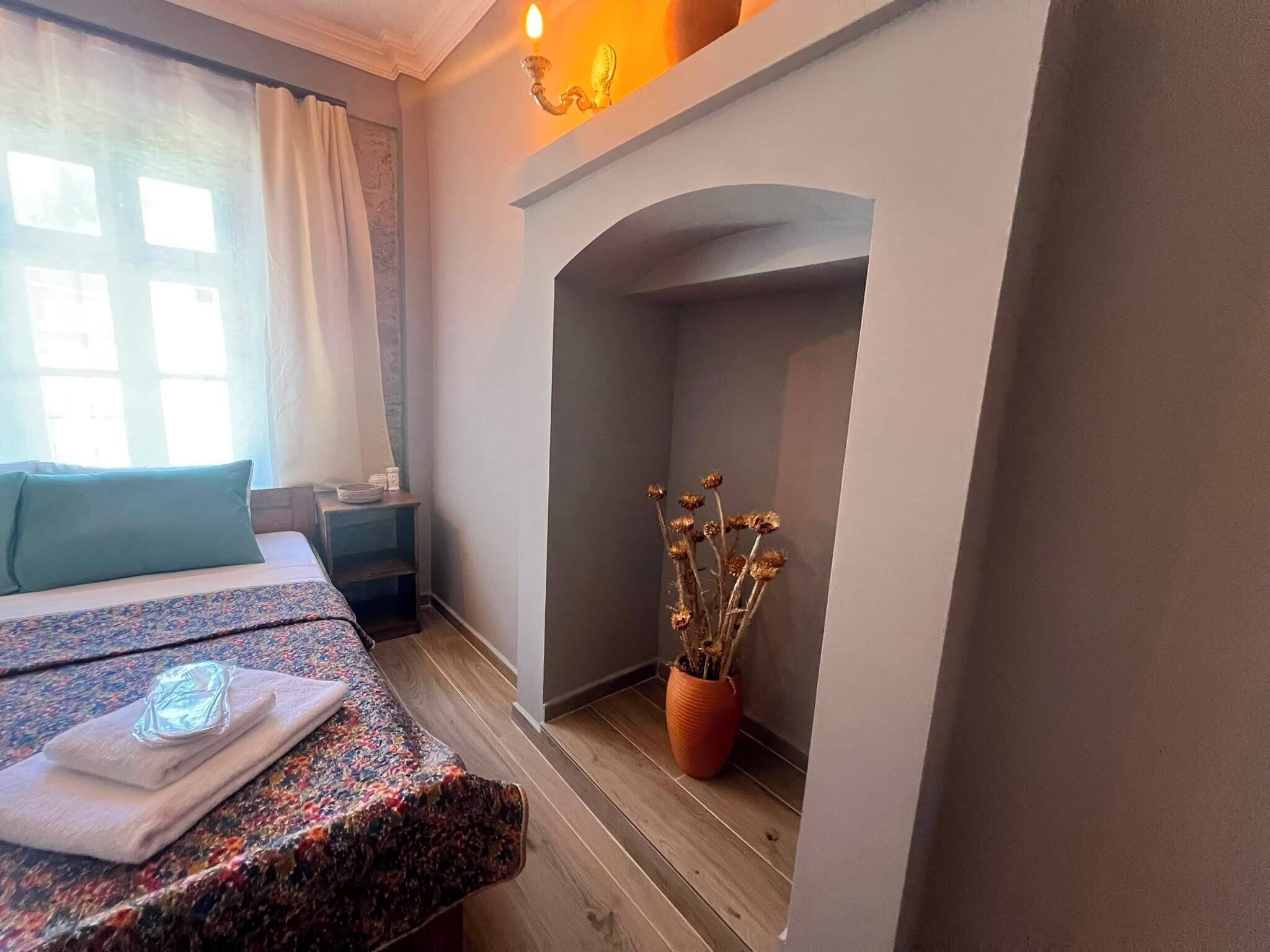 A bedroom with a bed, a nightstand, a potted plant, and a fireplace.