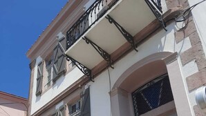 Un bâtiment à deux étages doté d’un balcon, d’un escalier menant à l’entrée et d’une porte surmontée d’une fenêtre.