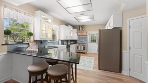 A modern kitchen with a central island, bar stools, a refrigerator, and a view of the outdoors. - Sweet Dreams Country Retreat - 9 Acres A Designer Country Escape (Trenton)