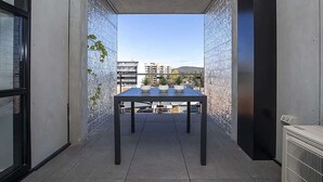 Ein Balkon mit Tisch, Blumentöpfen und Blick auf Gebäude.