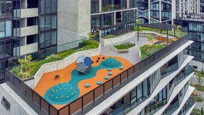 En takträdgård med lekredskap, sittplatser och utsikt över de omgivande byggnaderna.