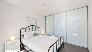 A modern bedroom with a bed, bedside tables, and a large wardrobe.