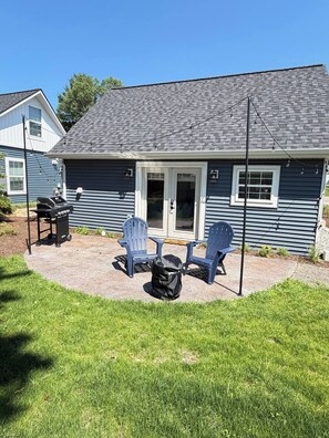 A house with a patio, outdoor seating, and a grill.
