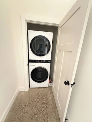 A laundry room with two stacked washers and dryers, a door, and a speckled floor.