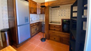 Una cocina compacta con armarios de madera, un refrigerador empotrado, un lavamanos y una estufa.