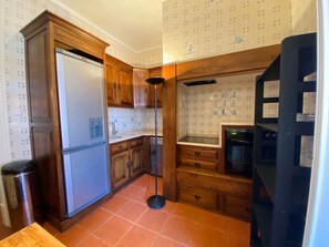 A compact kitchen with wooden cabinets, a built-in refrigerator, a sink, and a stove. - Perfect Flat in the Center (Lisboa)