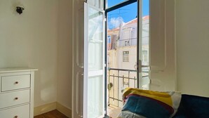 Una habitación con cama, cómoda y ventana con vista a edificios.