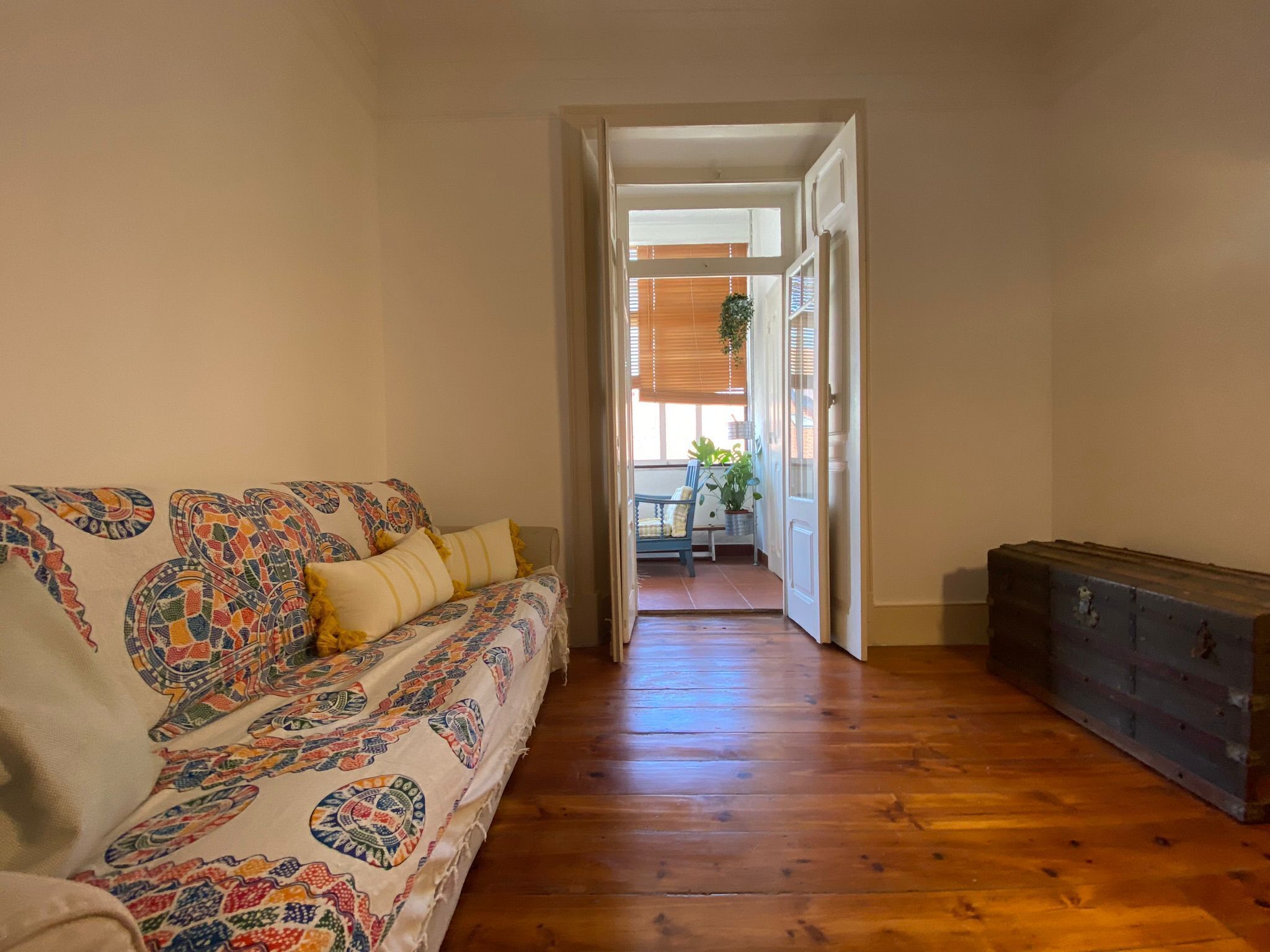 Un pasillo con piso de madera, un sofá con cojines estampados y un mueble azul.