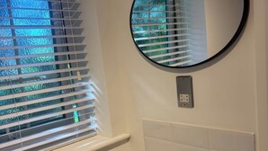 Un baño con ventana, un espejo redondo y un grifo negro.