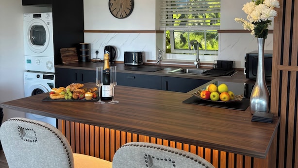 A modern kitchen with a central island, built-in appliances, pendant lighting, and a view through a window.