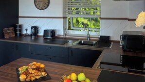 Una cocina moderna con estufa integrada, un lavamanos y una ventana con vistas a zonas verdes.