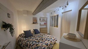 Ein Schlafzimmer mit Bett, Nachttisch, Lampe und Spiegel.